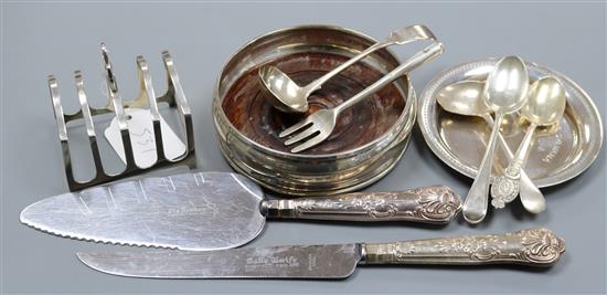 A modern silver wine coaster, a silver toastrack, an Egyptian white metal dish and seven items of flatware